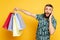 Shocked bearded guy with shopping bags on yellow