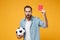 Shocked bewildered young man in blue shirt posing isolated on yellow orange wall background. People lifestyle concept