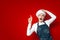 Shocked chef shows copyspace on red isolated background, shocked kitchen worker in uniform advertises place for text