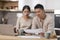 Shocked chinese spouses reading correspondence, kitchen interior