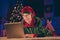 Shocked crazy elf read x-mas congratulation on laptop floor wear green costume in christmas evening house indoors with