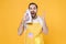 Shocked crazy young man househusband in apron doing housework isolated on yellow background studio portrait