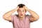 Shocked dazed young man in t-shirt holding head with both hands. emotional guy isolated on white background