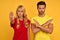 Shocked dissatisfied young couple, two friends man woman 20s in red and yellow empty blank t-shirts showing stop gesture with palm