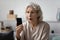 Shocked elderly lady staring at smartphone with open mouth