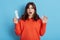 Shocked female holding menstrual cup and sanitary pad in hands, decides what to choose for period, stands with open mouth,