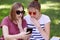 Shocked female teenagers look surprisingly at smart phone, recieve unexpected message, wears trendy sunglasses, pose against green