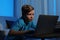 Shocked little child with laptop in dark room