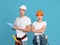Shocked Man And Woman In Protective Hardhats With Clipboard Over Blue Background