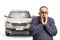Shocked mature man holding his face in front of a vehicle with broken windscreen