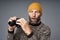 Shocked mature man in warm sweater and knitted hat holding binoculars