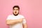 Shocked overweight guy in white t-shirt stands on pink background and points his finger away at copy space. A surprised