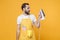 Shocked perplexed young man househusband in apron doing housework isolated on yellow wall background studio portrait