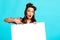 Shocked pinup lady pointing at blank banner on blue studio background, mockup for ad, promo, sale