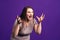 Shocked plus size model with wide open mouth on purple background