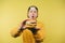 Shocked positive young man holds an appetizing burger in his hands and shows it to the camera on a yellow background