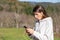 Shocked pretty young woman breathes fresh air in the park listening to music on headphones and holding a smartphone