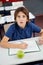 Shocked Schoolboy With Cheat Sheet Sitting At Desk