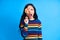 Shocked screaming woman covers her eye with colorful lollipop isolated on blue background