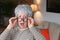 Shocked senior woman holding eyeglasses