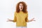Shocked, speechless and amazed redhead curly woman in yellow sweater losing speech from astonishment and shock, raise