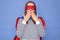 Shocked surprised amazed Caucasian brown haired woman wearing superhero costume and striped shirt isolated over blue background