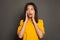 Shocked surprised black woman in yellow shirt on gray studio background