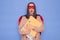 Shocked surprised brown haired woman wearing superhero costume holding paper folders posing  over blue background having