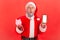 Shocked surprised santa claus holding smartphone with empty screen and piggy bank, cashback, online wallet