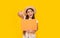 shocked teen kid with copy space on orange paper on yellow background. point finger