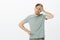 Shocked tired Caucasian man with bristle in earrings, holding palm on forehead and standing exhausted at camera