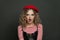 Shocked woman in red french style beret on black background