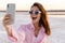 Shocked young girl in sunglasses taking a selfie by phone