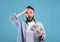 Shocked young guy holding lots of money, cannot believe his big win or luck over blue studio background