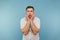 Shocked young man with bristles clings to his head and looks away with a surprised face on a blue background