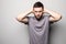 Shocked young man in plaid shirt holding over head with both hands over grey background