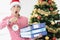 Shocked young woman holds alarm clock and stack of folders with documents on background of Christmas tree