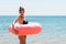 Shocked young woman inside donut rubber ring is standing in the cold water