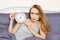 Shocked young woman waking up with alarm, overslept work, bad sleep insomnia. Girl hold clock when lying on bed in the morning