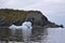 Shoe-shaped iceberg next to rugged cliffs in Twillingate Harbour