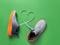 Shoelace heart symbol between gray textile sneakers with grooved orange sole on grassy green background. Laced up stylish mesh