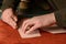 Shoemaker hands cutting terracotta suede leather in workshop. Closeup