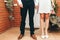 Shoes of groom and bride and her small wedding bouquet of pink roses with clasped hands after the ceremony. Wedding concept.