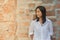 Shoot photo Asian woman portrait wear white shirt and looking sideways with red brick background.