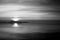 A shoot of a sunset over a lake, with sun coming down behind and island and many diagonal lines created by clouds and