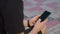 shooting advertising, a young guy in the park sits on a bench in black clothes and plays on the phone.