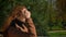 Shooting from behind caucasian beautiful brunette woman is walking in green sunny park outdoor, city background and