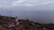 Shooting from drone of a lighthouse on a hill by the sea connecting to the sky on the horizon