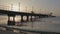 Shooting with drone at sunset in a bay. The drone passes under a pier.