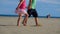 Shooting of legs of a boy and girl walking along the beach while holding hands